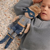 Child holding a plush Jim toy doll with a superhero outfit on a patterned surface