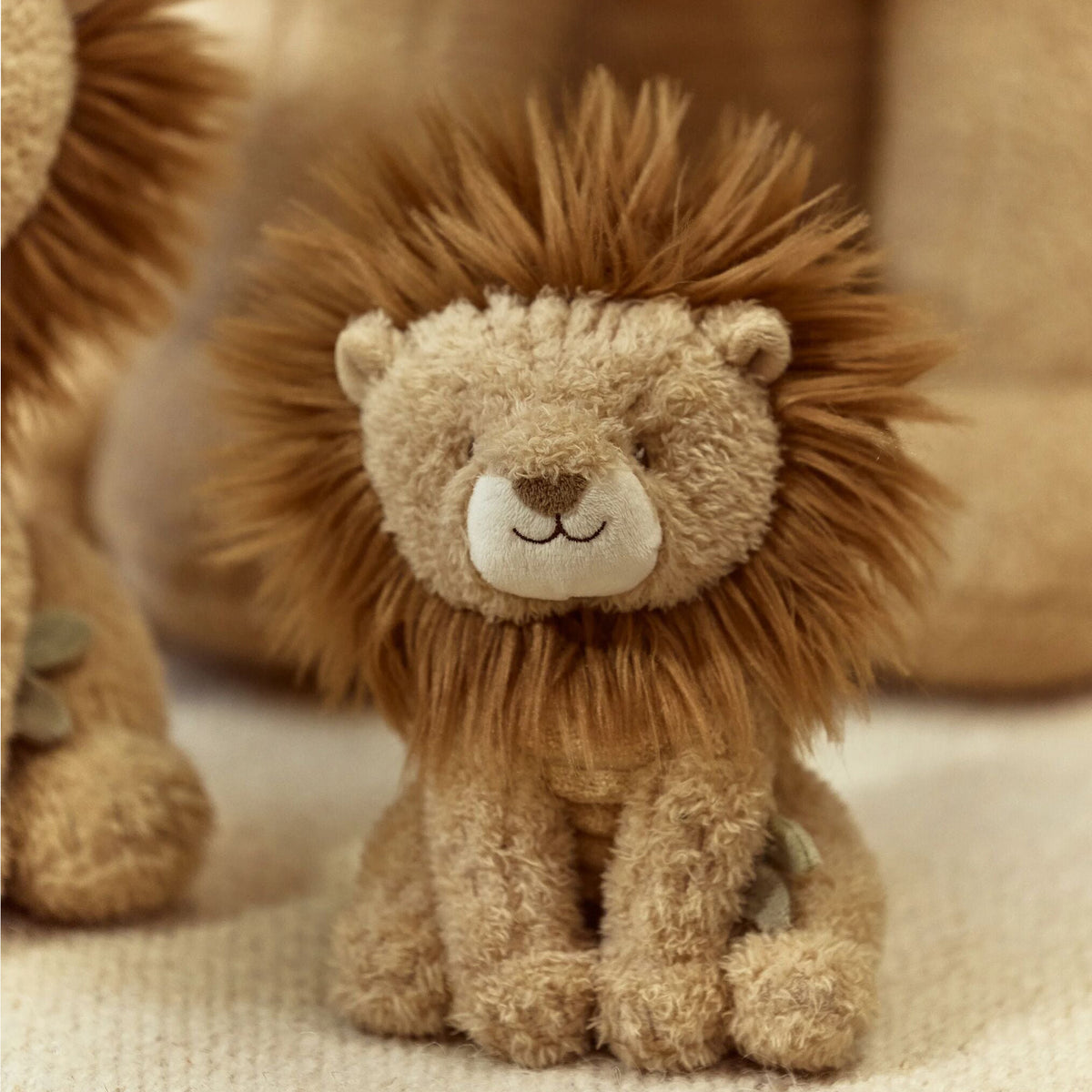 Plush lion toy with a soft texture on a beige background