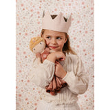 Young girl holding a princess doll with a floral patterned background