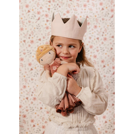 Young girl holding a princess doll with a floral patterned background