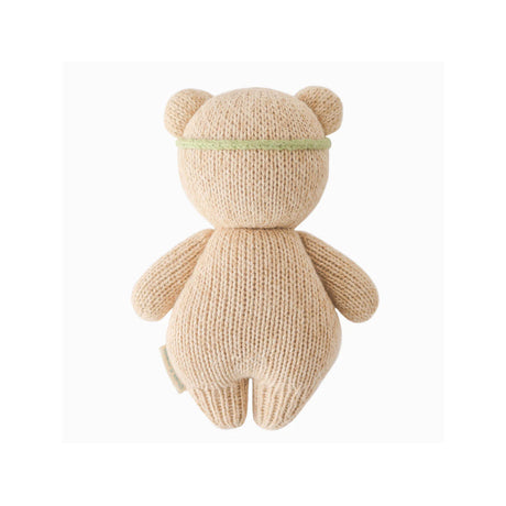 Knitted teddy bear with a green headband on a white background