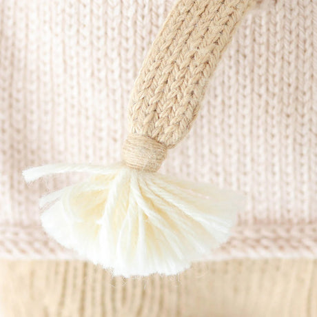 Close-up of a woven handle with a tassel on a textured beige background