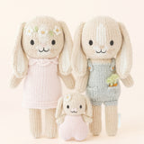 Three knitted bunny dolls in various outfits on a light background