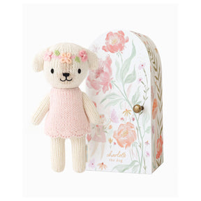 Knitted dog toy with floral crown next to a floral-patterned box on a white background