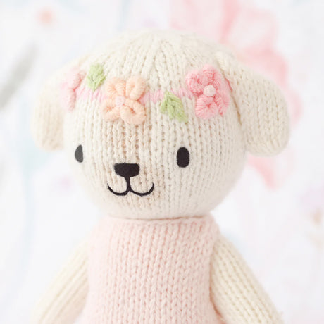 Knitted dog with floral headband on a light background