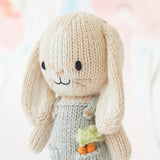 Close up of knitted bunny toy with carrots on a soft, multicolored background