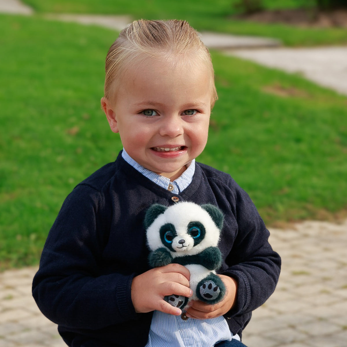 A young child holds a small panda plush toy outdoor