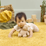 Baby lying on yellow rug cuddling Winnie the Pooh 100 soft small toy