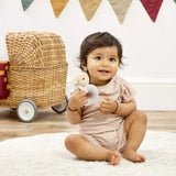 Baby sitting on a white rug holding a harry potter teething ring with colourful flags in the background.