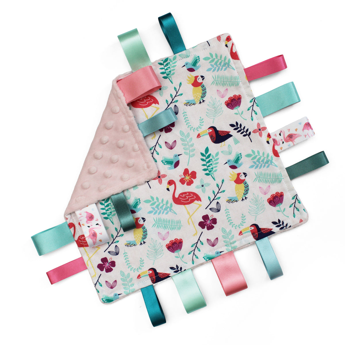 A square baby comforter featuring a colourful tropical print of flamingos, toucans, and foliage on a white with a pink minky dot reverse side and colourful matching satin ribbon tabs.