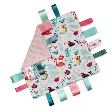 A square baby comforter featuring a colourful tropical print of flamingos, toucans, and foliage on a white with a pink minky dot reverse side and colourful matching satin ribbon tabs.