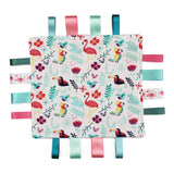 A square fabric sensory baby soother with a colourful tropical pattern featuring flamingos, toucans and leaves on a white background, finished with eight hanging ribbon tabs in teal, pink, mint, and dark green.