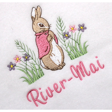 Embroidered design of a Flopsy bunny rabbit with flowers and the name 'River-Mai' on a white background