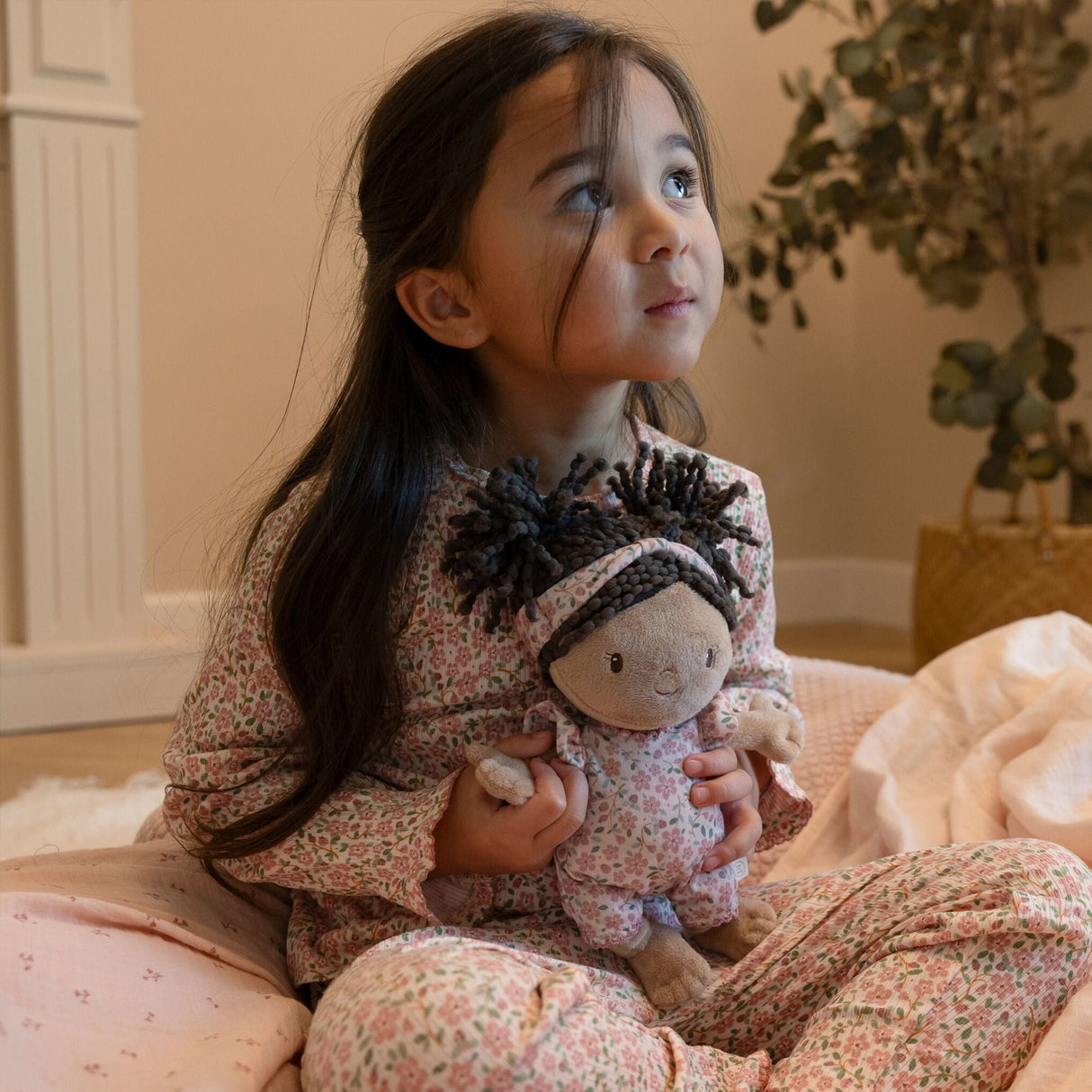 Young girl in floral pyjamas sitting on bed cuddling Little Dutch Baby Doll Evi