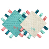 Two square textured fabric taggy blanket comforter with colorful ribbons and embroidered names on a white background