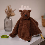 A plush brown moose comforter toy with white antlers sits on a white tabletop