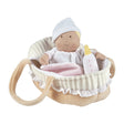 Baby doll in a crib with a bottle and blanket on a white background