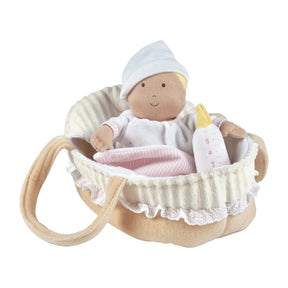 Baby doll in a crib with a bottle and blanket on a white background