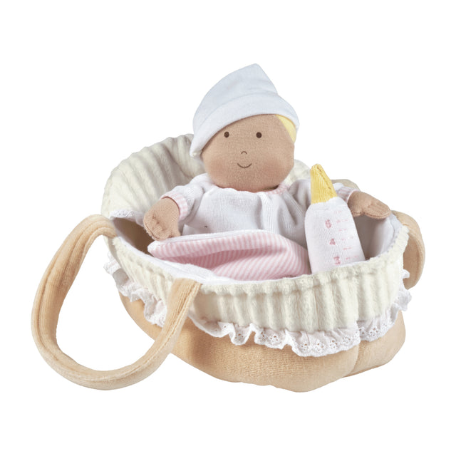 Baby doll in a crib with a bottle and blanket on a white background