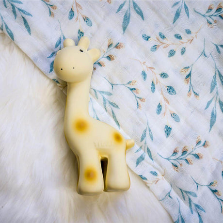 Giraffe-shaped teething toy on a soft, patterned fabric background