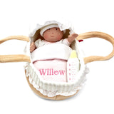 Soft baby doll in a basket with personalised name on blanket on a white background