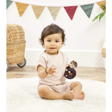 Baby sitting on a white rug with a Plush toy resembling harry potter holding a black plush ring