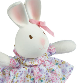 White rubber bunny toy with a pink bow and floral dress on a white background