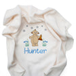 A cream-coloured plush fleece baby blanket with a custom embroidered design of Makka Pakka, blue flowers, stars, and the name in blue embroidery.