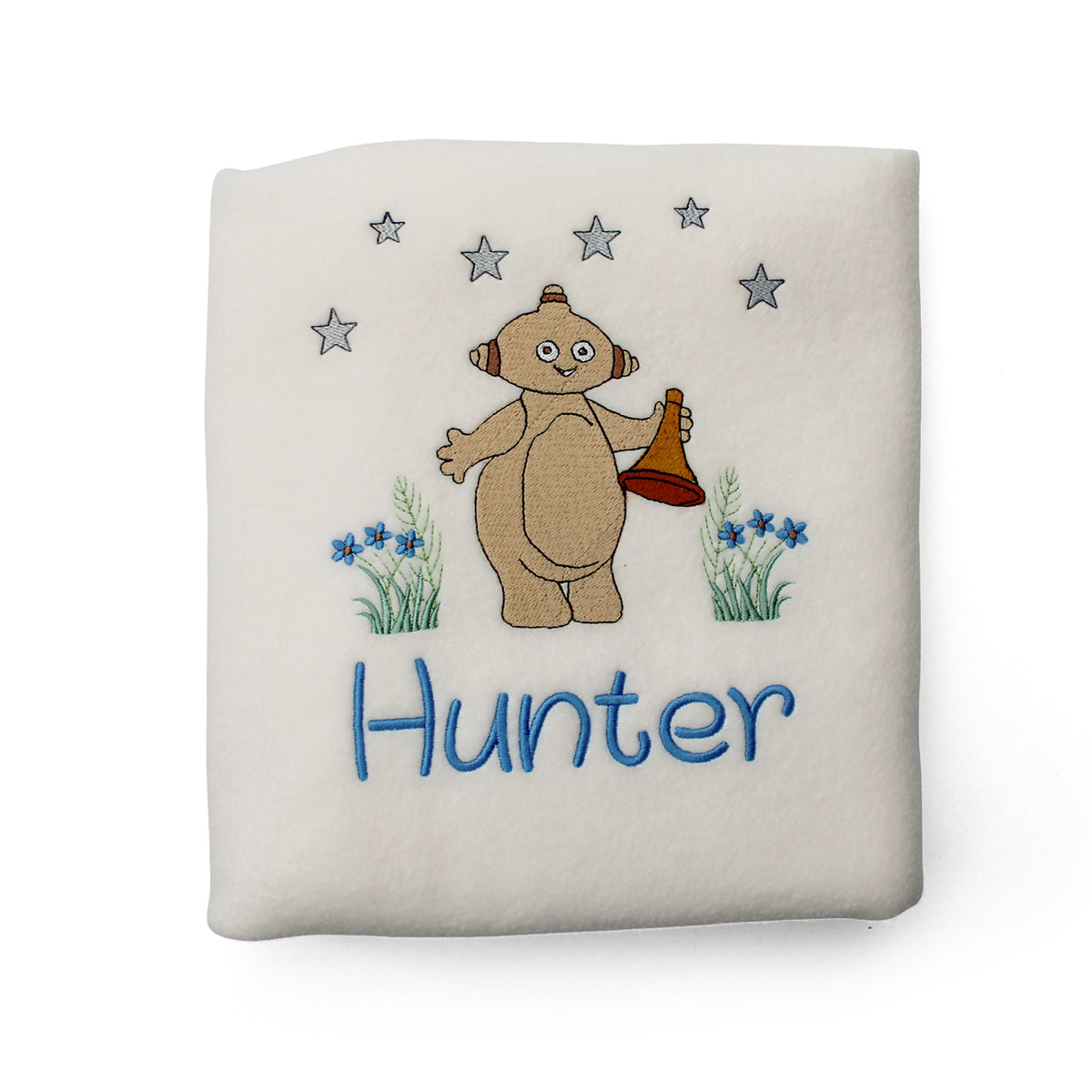 A cream-coloured plush fleece baby blanket with a custom embroidered design of Makka Pakka, blue flowers, stars, and the name in blue embroidery.