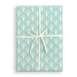 Gift wrap with a blue and white geometric pattern and a white ribbon on a white background