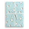 A Patterned blue gift wrap present with white storks holding a blue bundle and blue leaves with purple flowers wrapped with white satin ribbon