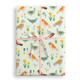 Gift wrap with bird and flower pattern tied with a pink ribbon on a white background