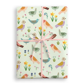 Gift wrap with bird and flower pattern tied with a pink ribbon on a white background
