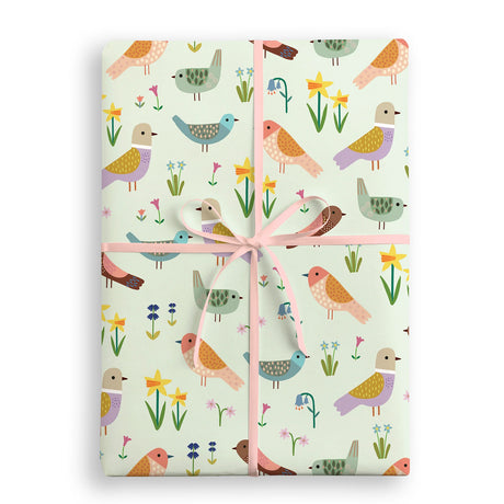 Gift wrap with bird and flower pattern tied with a pink ribbon on a white background