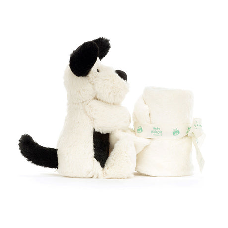 White plush dog toy with black accents next to a white pouch on a white background