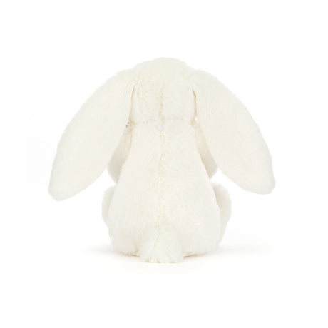A plush toy of a white bunny holding a carrot with green leaves.