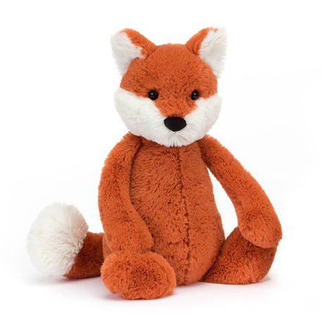A plush toy depicting a fox cub with fluffy white ears, feet, and tail-tip, sitting with a reddish-brown body.