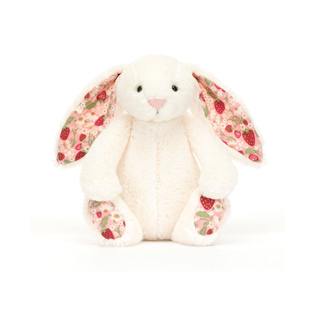 A small plush toy resembling a cream-colored bunny with soft cotton ears and feet, featuring a strawberry and cream flower pattern on a white backdrop.