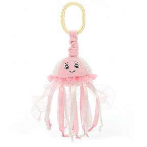 A pink Jellycat sea streamer jellyfish jitter with a smiling face and frilled tentacles, complete with a yellow ring for attachment.