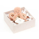 Coral coloured plush octopus toy in a gift box with a muslin swaddle with octopus print