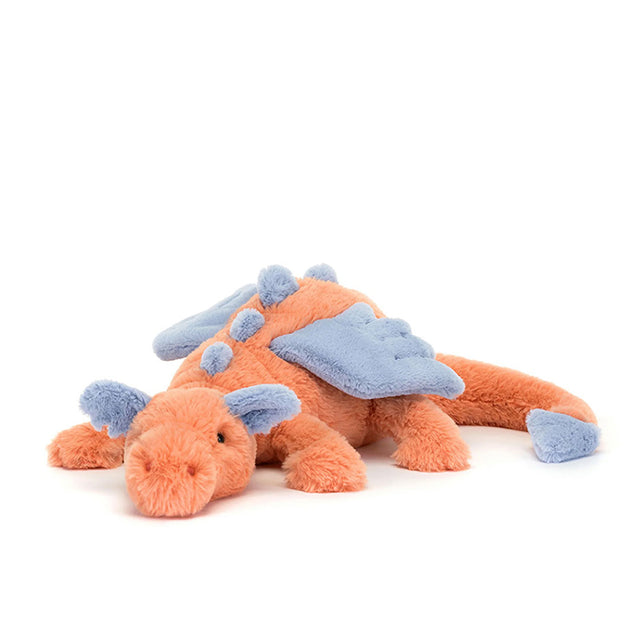 A plush toy representing a dragon with coral and blue colors, lying down with a content expression.