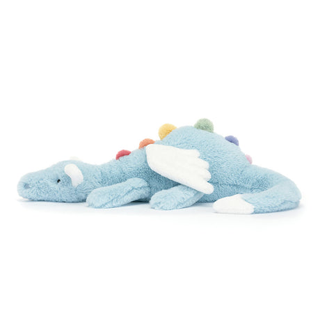 A plush toy resembling a sky blue dragon with rainbow-colored spines, cloud-white wings, and a snout. The dragon is in a lying pose with a serene expression.