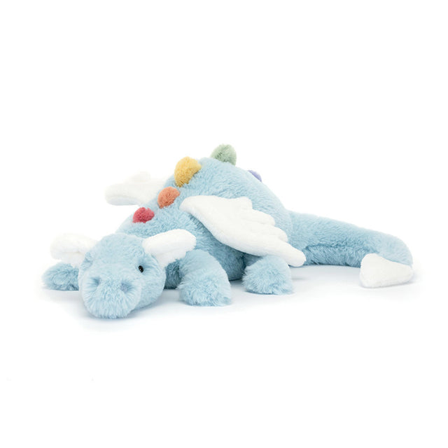 A plush toy resembling a sky blue dragon with rainbow-colored spines, cloud-white wings, and a snout. The dragon is in a lying pose with a serene expression.