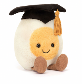 A plush toy resembling a smiling boiled egg wearing a black graduation cap with a golden tassel.