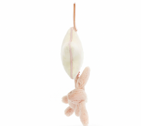 A plush blush pink bunny hanging from a star-shaped musical pull with a cream ribbon.