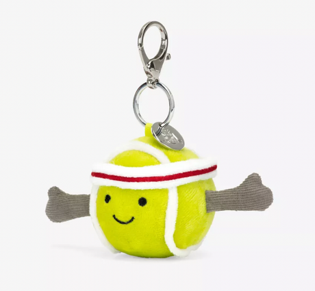 A plush toy in the shape of a yellow tennis ball with red and white details, wearing a white and red headband, attached to a silver clip and chain.