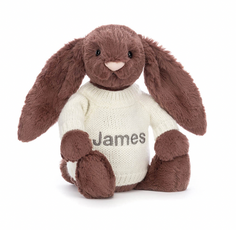 A beige plush toy in the shape of a bunny with long ears, wearing a white jumper with the name 'James' embroidered on the back.
