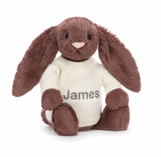 A beige plush toy in the shape of a bunny with long ears, wearing a white jumper with the name 'James' embroidered on the back.