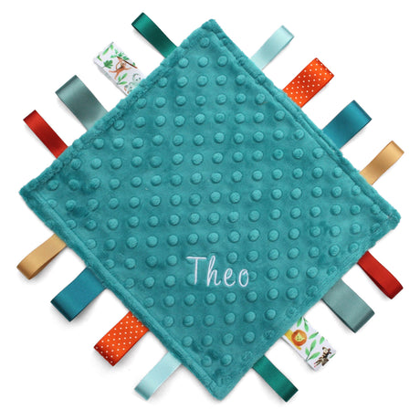 A handmade baby taggy comforter with  plush minky fabric, and decorated with double-sided satin ribbon tags in various colours. Personalised with the name Theo