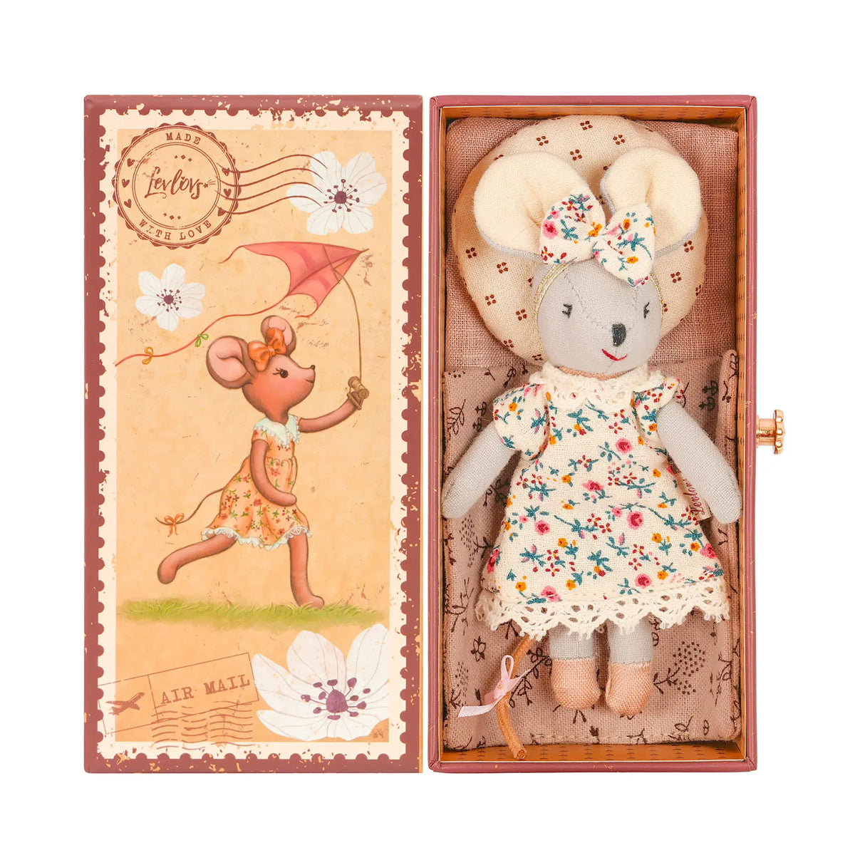 Stuffed cloth mouse toy in a floral dress and headband bow laying on bedding with a matching illustration gift box
